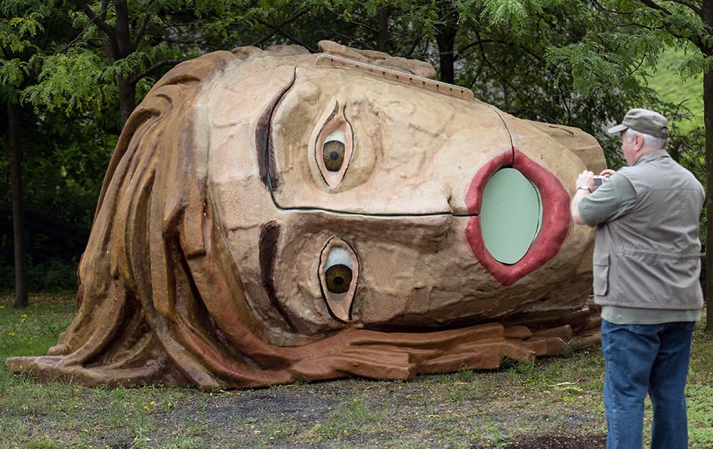 A man takes a pictures of the sculpture 'The Heads, Claudia & Hermann' of the Dutch studio Van Lieshout, in Bochum, western Germany.