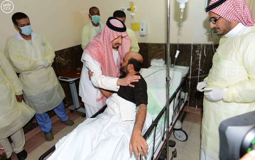 In this photo released by the Saudi Press Agency SPA, the governor of Asir, Prince Faisal bin Khaled bin Abdulaziz, center left, comforts an injured man, who was wounded in a suicide bombing attack on a mosque inside a police compound, in the city of Abha, the provincial capital of Asir, Saudi Arabia.