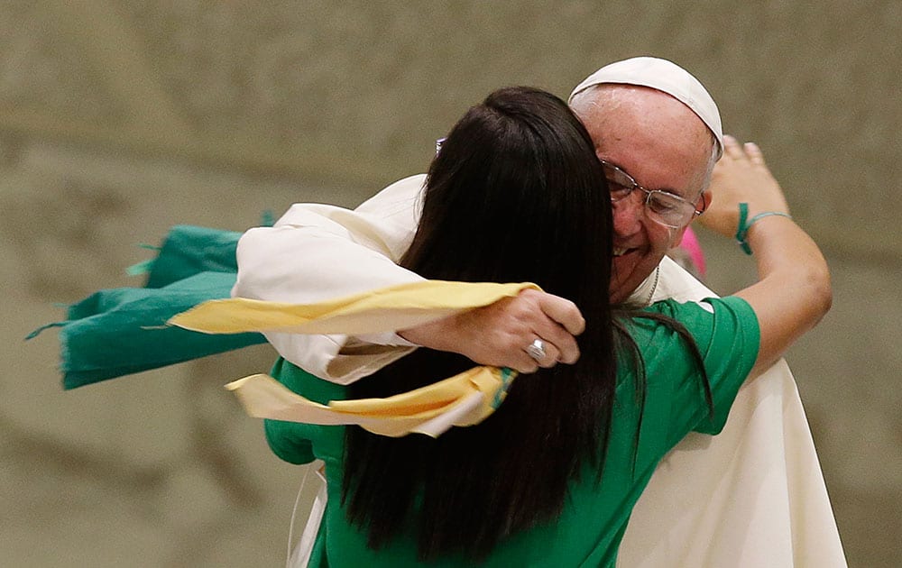 Pope Francis hugs a girl during a meeting with the Youth Eucharistic Movement in the Paul VI hall at the Vatican.