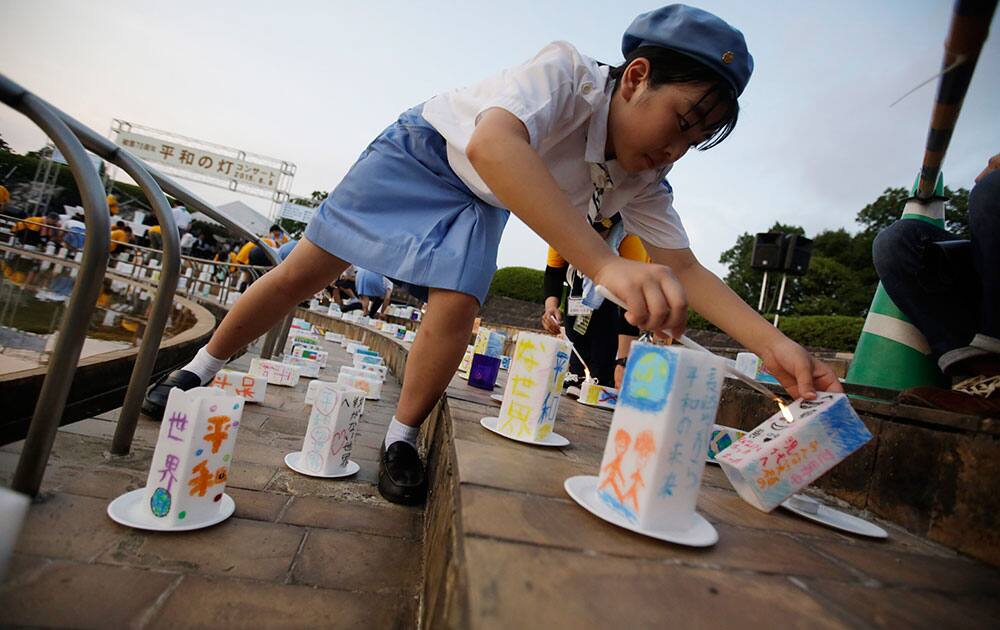 A girl scout lights paper lanterns which are placed for the victims of the atomic bombing on Nagasaki on the eve the 70th anniversary of the Nagasaki Atomic Bombing at the Peace Park in Nagasaki.