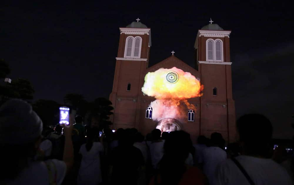 Visitors watch a computer-generated video of a mushroom cloud of 1945 atomic bomb dropped over the city projected on Urakami Cathedral on the eve the 70th anniversary of the Nagasaki Atomic Bombing in Nagasaki