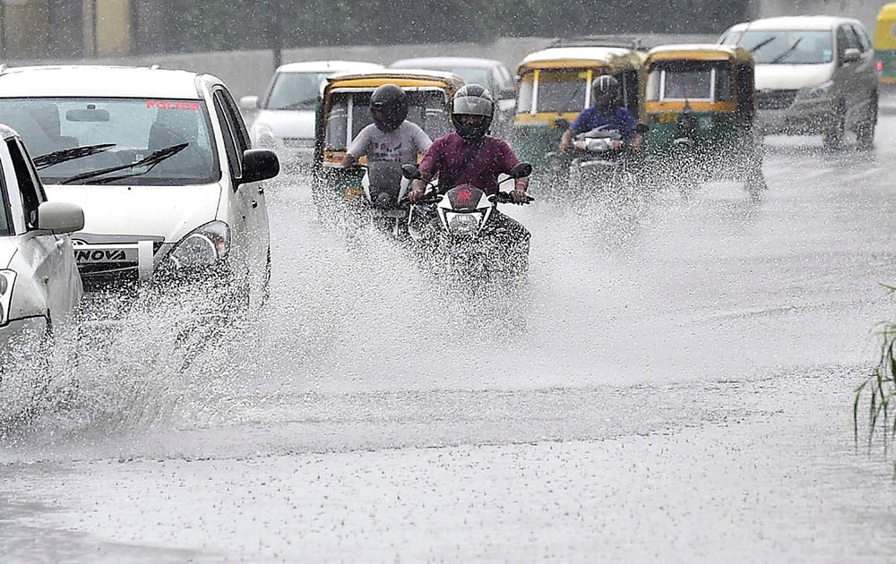 Vehicles move through a waterlogged road during the downpour, in New Delhi.