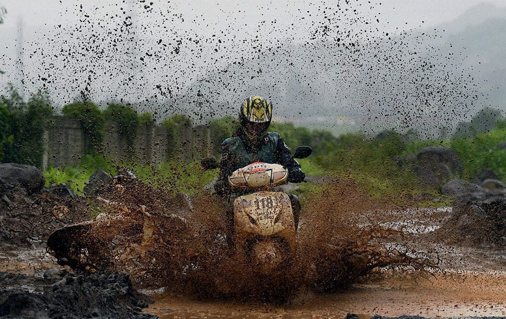 A scooter rider in action while crossing a rivulet during the Gulf Monsoon Scooter Rally, in Mumbai.