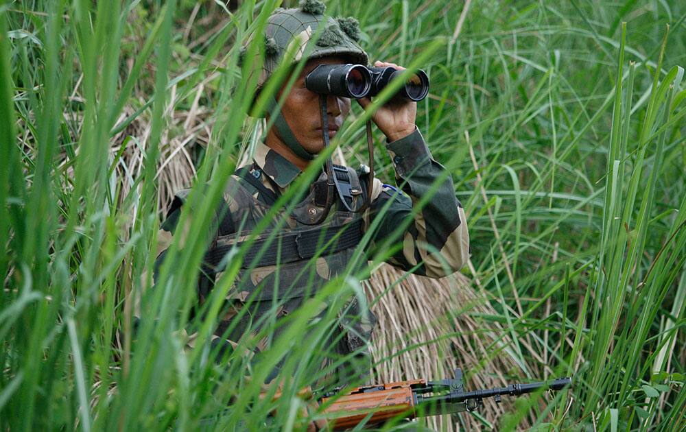 An Indian Border Security Force (BSF) soldier keeps watch along the Pargwal area of India-Pakistan international border in Akhnoor, Jammu and Kashmir.