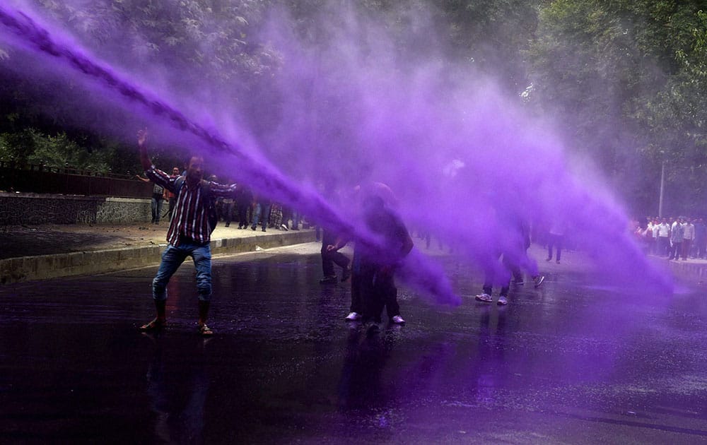 Police uses colored water to disperse government employees during their march towards Chief Ministers Residence to protest in support of their long pending demands, at Polo View in Srinagar.