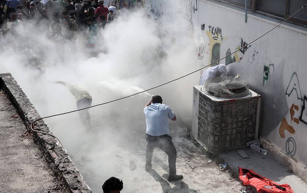 A policeman tries to disperse hundreds of migrants by spraying them with a fire extinguisher, during a registration procedure which was taken place at the stadium of Kos town, on the southeastern island of Kos, Greece.