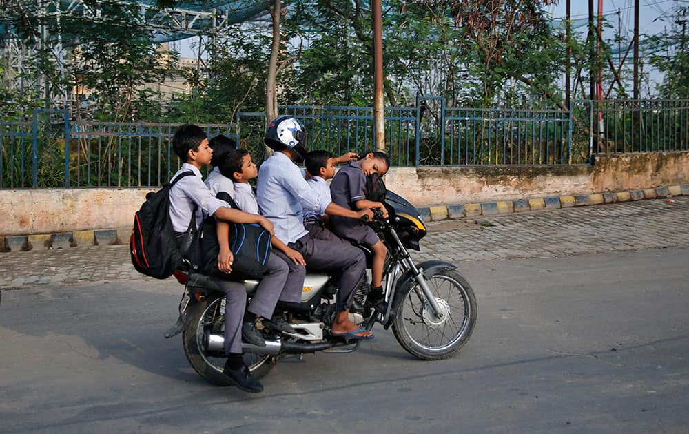 A girl sleeps as a man rides a motorbike to drop Indian children to school in the morning in Lucknow, India.