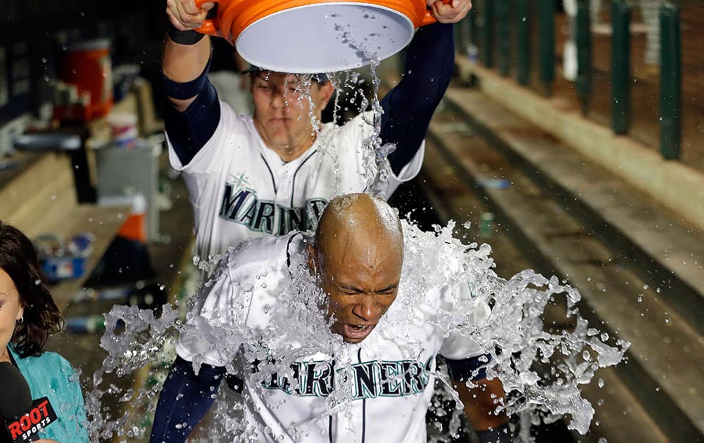 Seattle Mariners' Austin Jackson is hit with a bucket of water by teammate Logan Morrison as Jackson is interviewed after hitting in the winning run against the Baltimore Orioles in the 10th inning of a baseball game in Seattle.