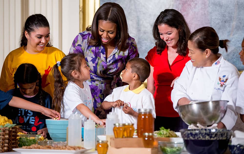 First lady Michelle Obama, accompanied by Lets Move! Executive Director Deb Eschmeyer, second from right, talks with Oneida Gonzalez, 5, center left, and Jefferson Lopez-Martinez, 5, center right, of CentroNia Daycare Center in Washington, D.C. as they help prepare food harvested from the White House Kitchen Garden along with fellow children from all over the country who participated in events with the