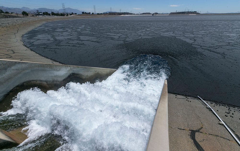Water flows into the Los Angeles Reservoir, which has been covered with over 90 million black plastic balls in the Sylmar area of Los Angeles .