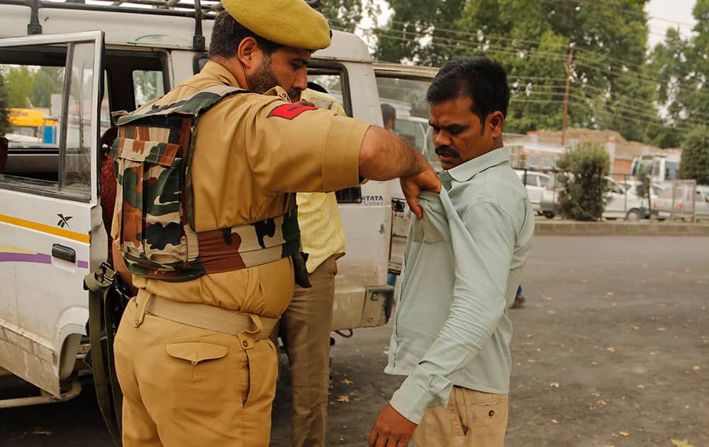 A policeman frisks a civilian at a busy road as part of enhanced security ahead of India’s Independence Day in Srinagar.