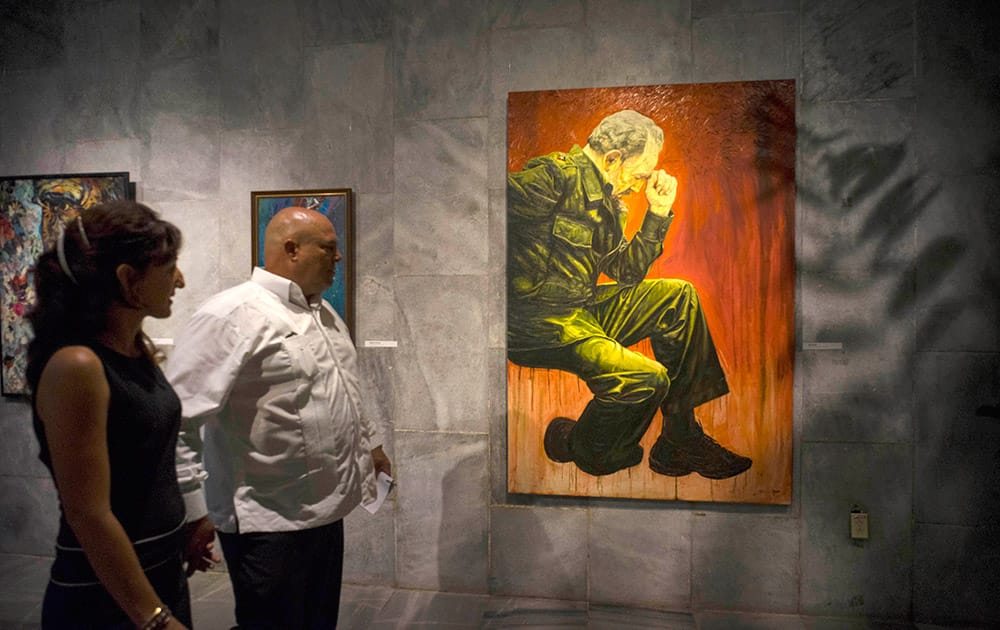 Alex Castro, second right, photographer and son of Cuban leader Fidel Castro, accompanied by his wife, looks at an exhibition about his father, at the Jose Marti Memorial in Havana.