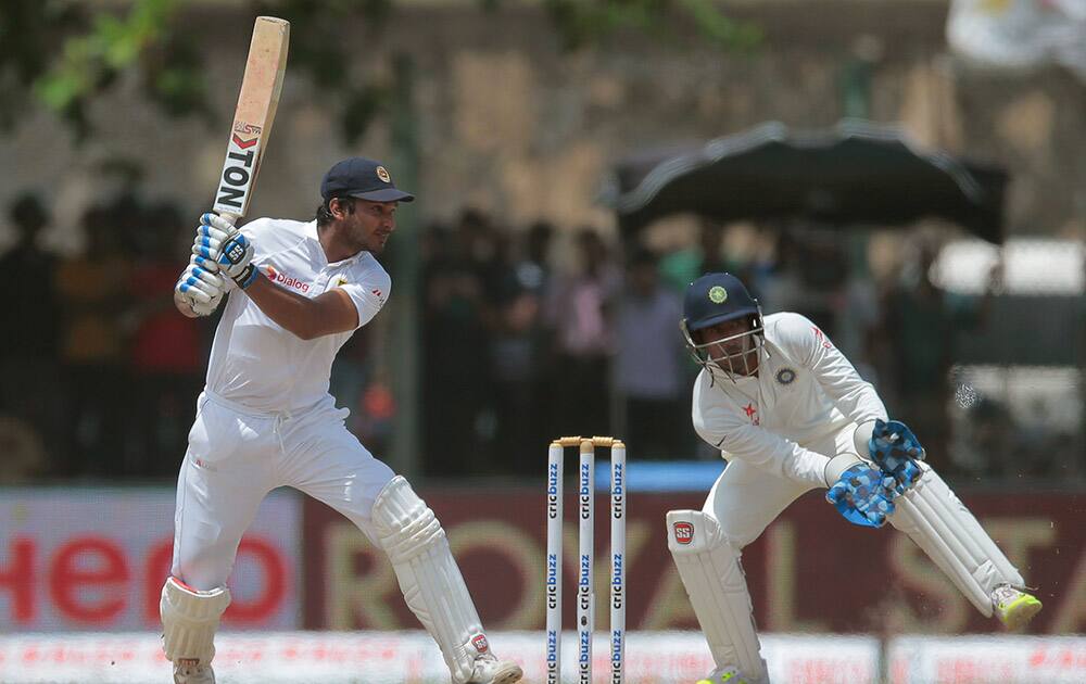 Sri Lanka's Kumar Sangakkara plays a shot as India's wicketkeeper Wriddhiman Saha watches during the third day of the first cricket test match between India and Sri Lanka in Galle, Sri Lanka.