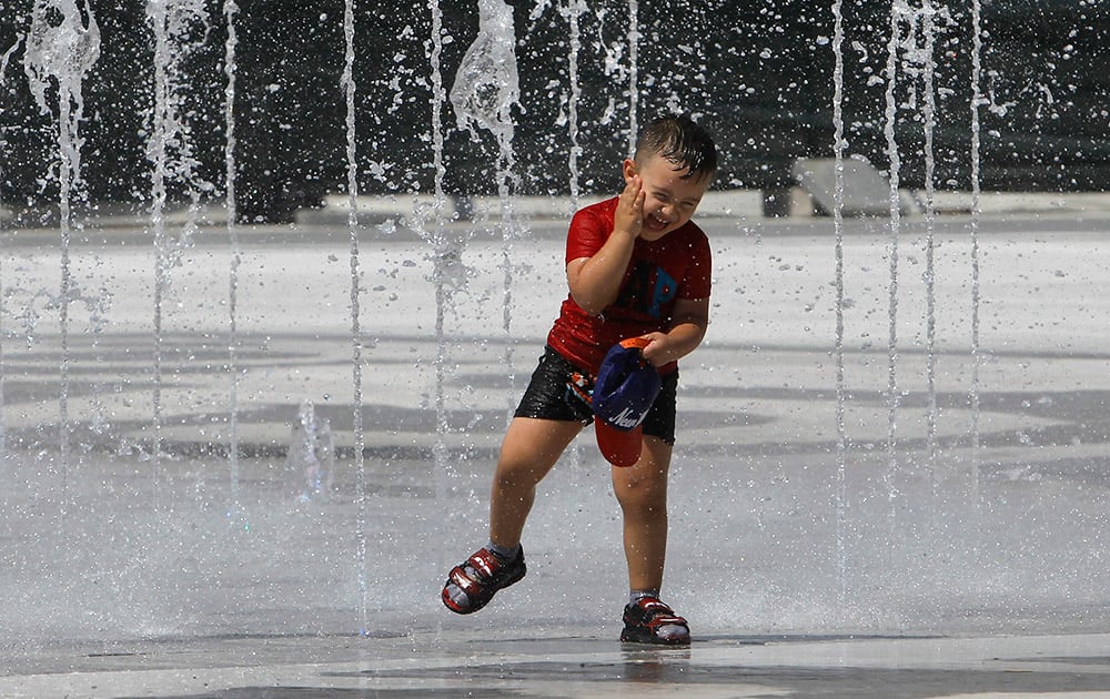 A young boy chills out in hot weather in a fountain, in Skopje, Macedonia.