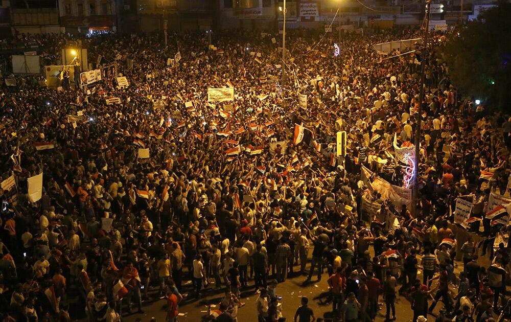 Protesters chant in support of Iraqi Prime Minister Haider al-Abadi as they wave national flags during a demonstration in Tahrir Square in Baghdad, Iraq.