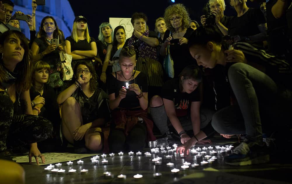 Women light candles in memory of women killed in domestic violence during a protest against violence against women in Madrid, Spain.