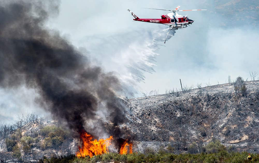 A helicopter makes a water drop on a wildfire in Angeles National Forest above Azusa, Calif.