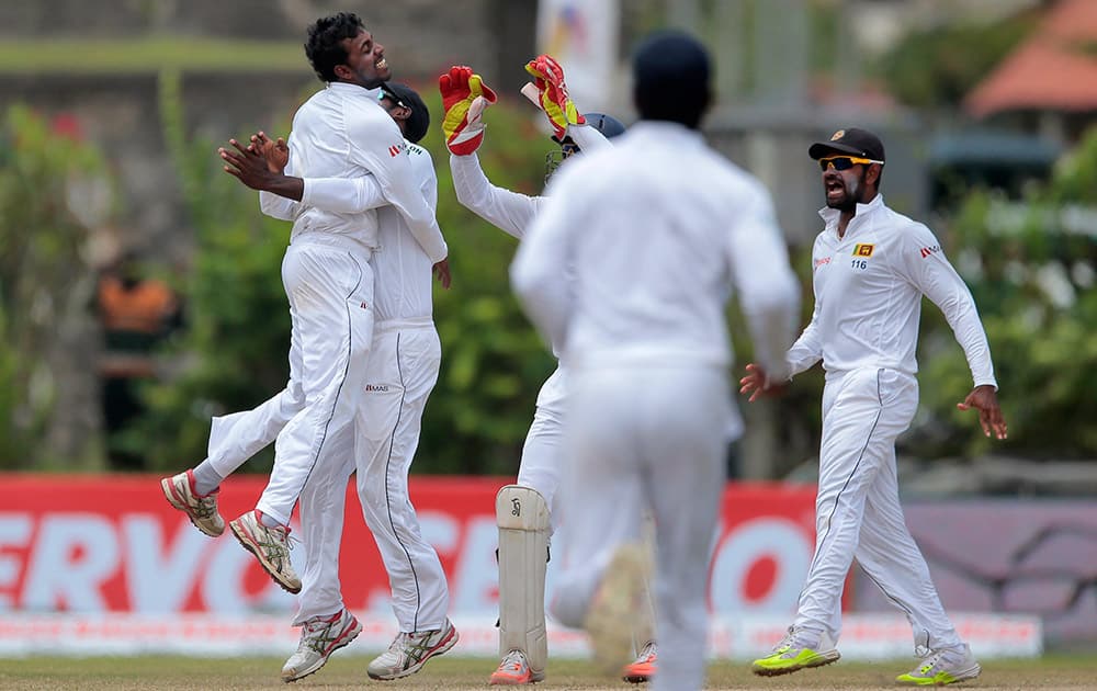 Tharindu Kaushal celebrates with teammates the dismissal of Virat Kohli during the fourth day of their first test cricket match in Galle, Sri Lanka. Sri Lanka won by 63 runs.