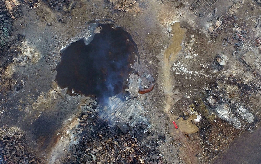 Smoke rises from debris near a crater that was at the center of a series of explosions in northeastern China's Tianjin municipality as seen from an aerial view.