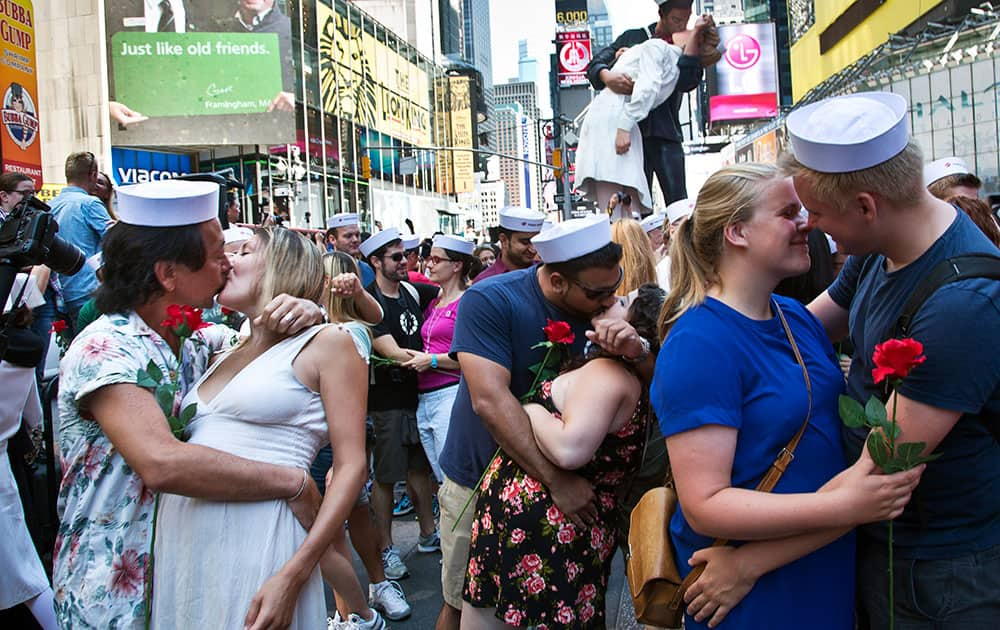 Married couple Kenji and Kristen Kawasaki, far left, join others as they re-enact the iconic 1945 Alfred Eisenstaedt kiss photo, Thursday, Dec. 10, 2015, in New York's Times Square. 