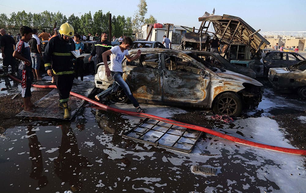 Civilians and security forces gather at the scene of a deadly car bomb in the Habibiya neighborhood of Sadr City, Baghdad, Iraq. An Iraqi police official says the explosion at a popular car dealership in eastern Baghdad.