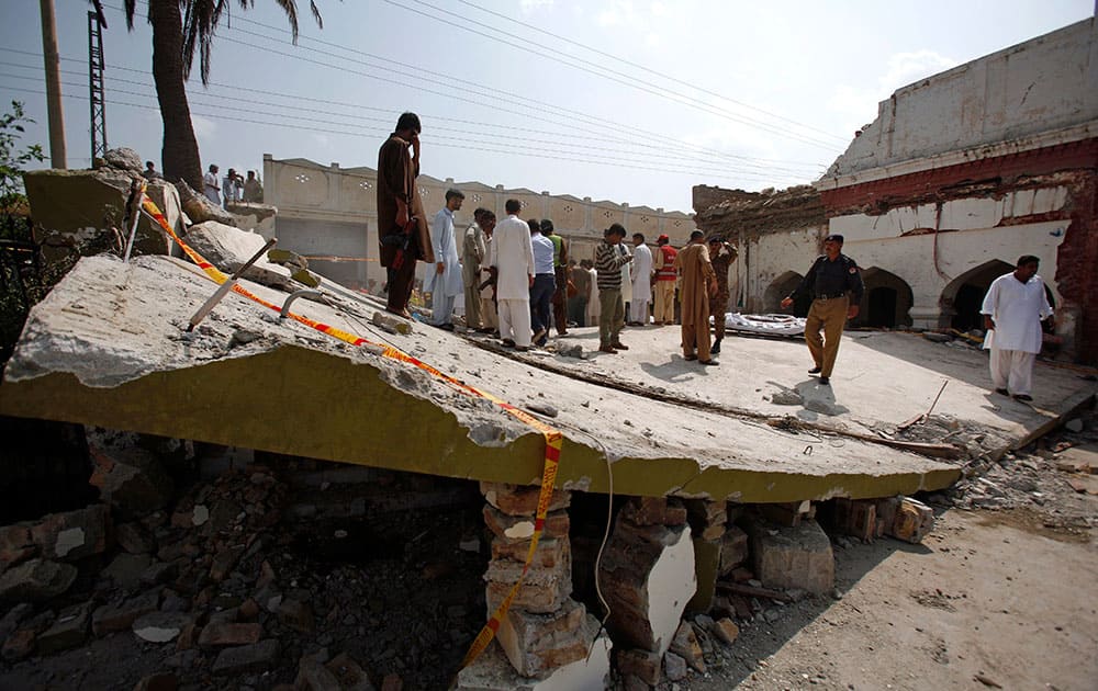 A Pakistani police officer and rescue workers gather at the site of suicide bombing in Shadi Khan, some 80 kilometers (50 miles) northwest from Pakistani capital.