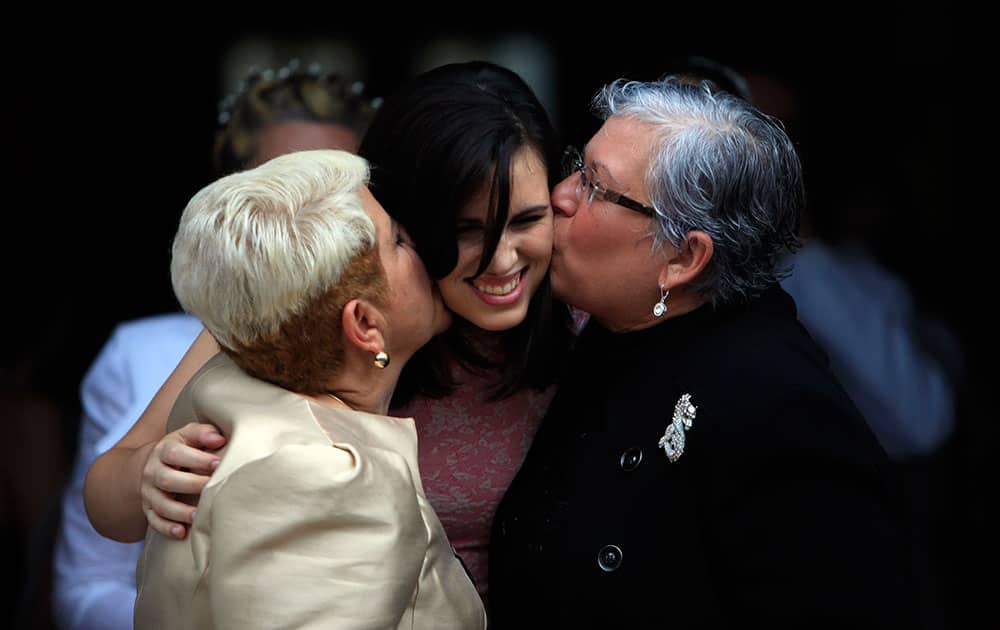 Ada Conde and Ivonne Alvarez kiss their daughter Adita Alvarez during a mass same-sex wedding in San Juan, Puerto Rico.