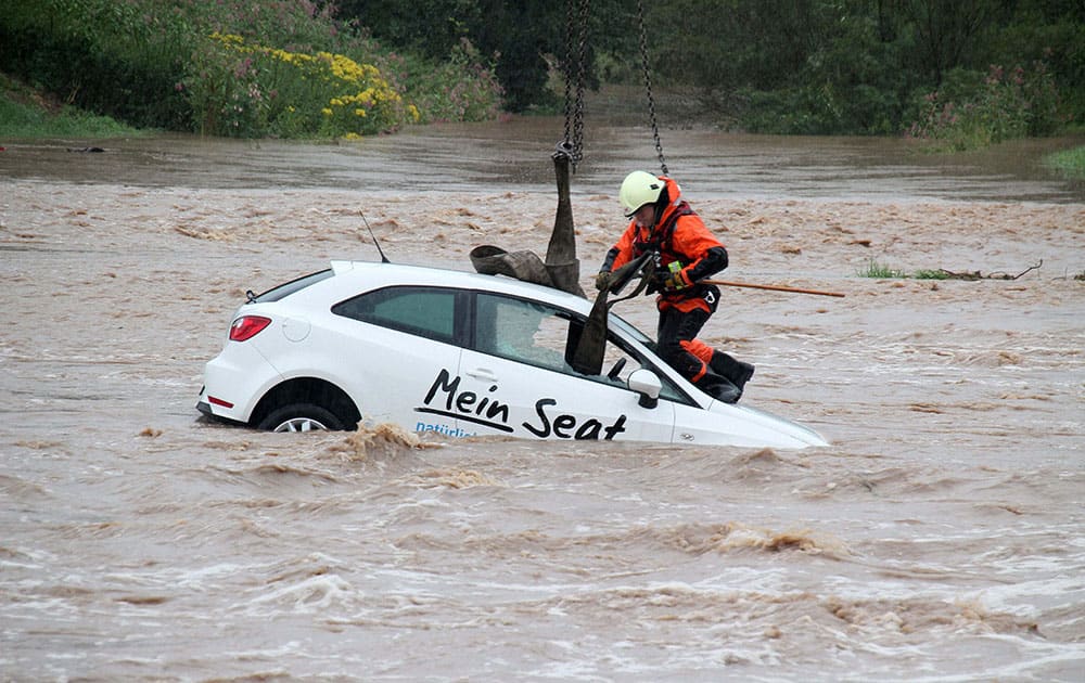 A firefighter attaches straps to a car drifting in the floods to prepare its recovery from a flooded area by a crane in Goettingen, Germany.