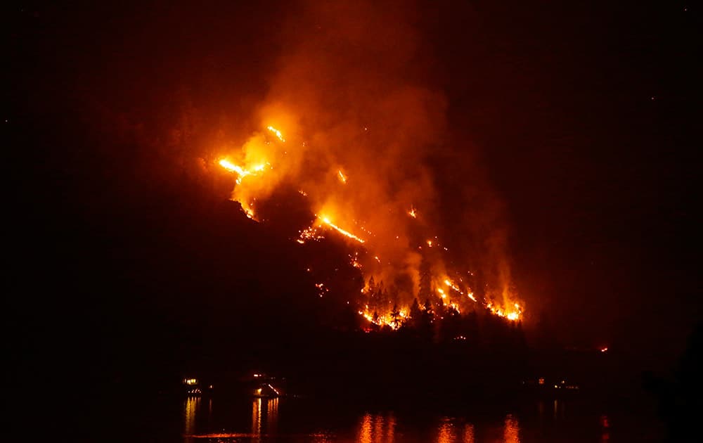 Timber burns in the First Creek fire near lakeside structures on the western shore of Lake Chelan, near Chelan, Wash.