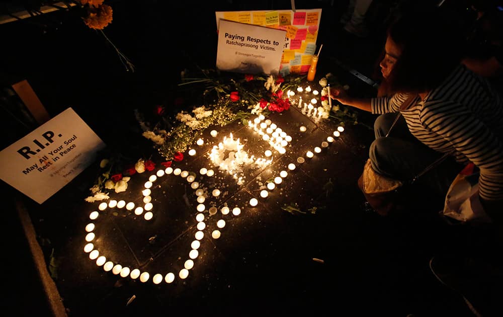 A woman lights a candle for the victims near the Erawan Shrine at Rajprasong intersection the day after an explosion in Bangkok, Thailand.