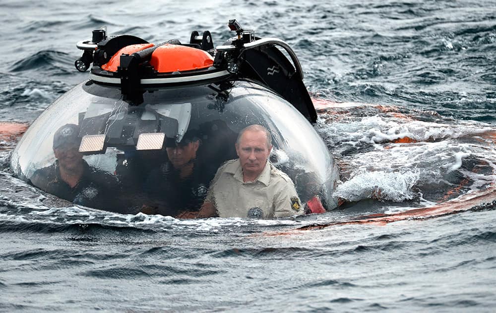 Russian President Vladimir Putin, right, sits on board a bathyscaphe as it plunges into the Black sea along the coast of Sevastopol, Crimea. President Vladimir Putin plunged into the Black Sea to see the wreckage of a sunk ancient merchant ship which was found in the end of May.