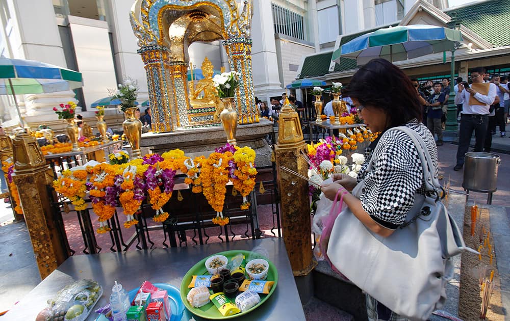A woman pays respects at the Erawan Shrine at Rajprasong intersection in Bangkok, Thailand.
