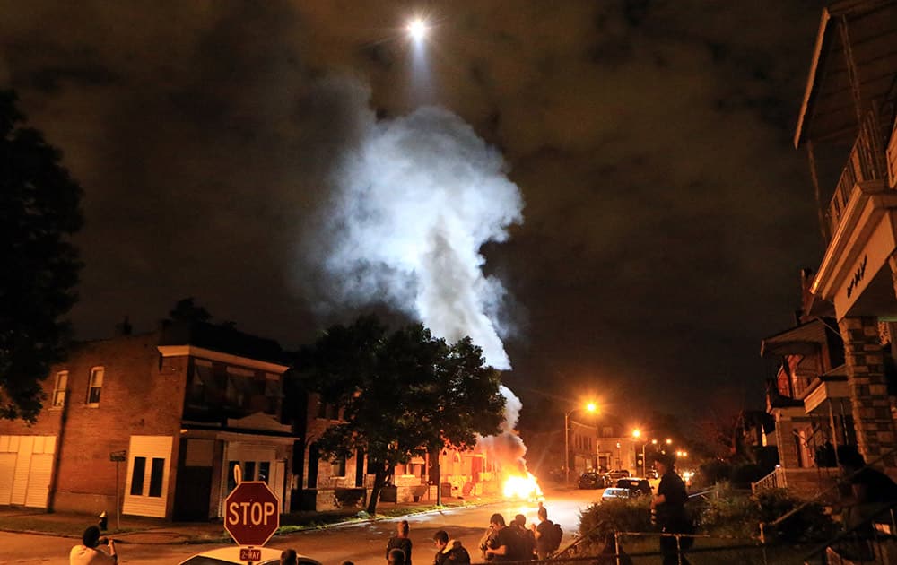 A police helicopter illuminates a burning car, after it was set ablaze following a fatal officer-involved shooting, in St. Louis. A black 18-year-old fleeing from officers serving a search warrant at a home in a crime-troubled section of St. Louis was fatally shot Wednesday by police after he pointed a gun at them, the city's police chief said.