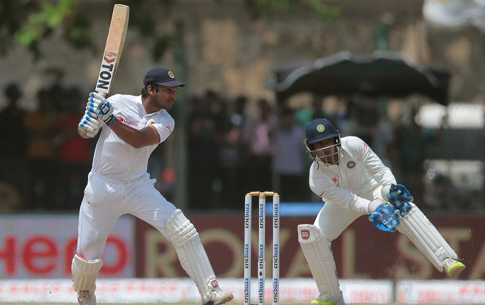 Sri Lanka's Kumar Sangakkara plays a shot as India's wicketkeeper Wriddhiman Saha watches during the third day of the first cricket test match between India and Sri Lanka in Galle, Sri Lanka.