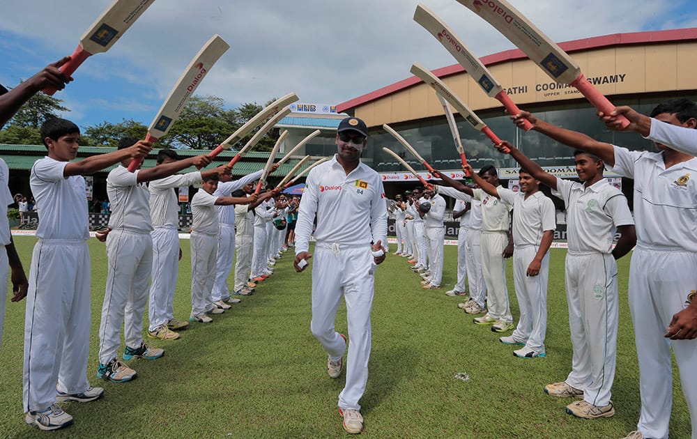 Sri Lankan cricketer Kumar Sangakkara, center, is greeted with an arch of bats as he enters the field for the last match of his test cricket career, the second test cricket match between Sri Lanka and India in Colombo.