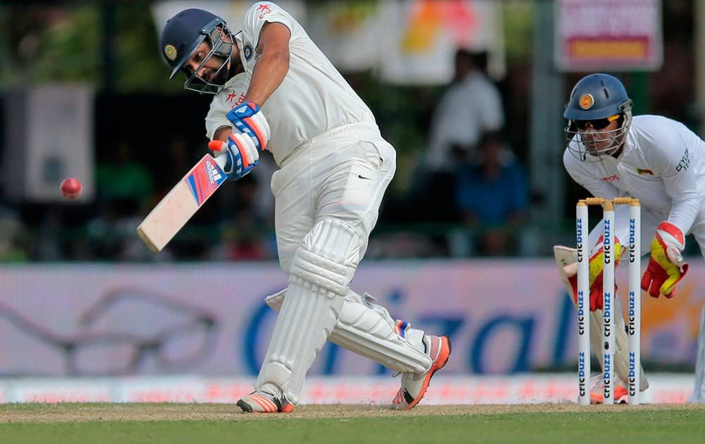 Rohit Sharma plays a shot as Sri Lanka's wicket keeper Dinesh Chandimal watches during the first day's play of their second test cricket match in Colombo, Sri Lanka.