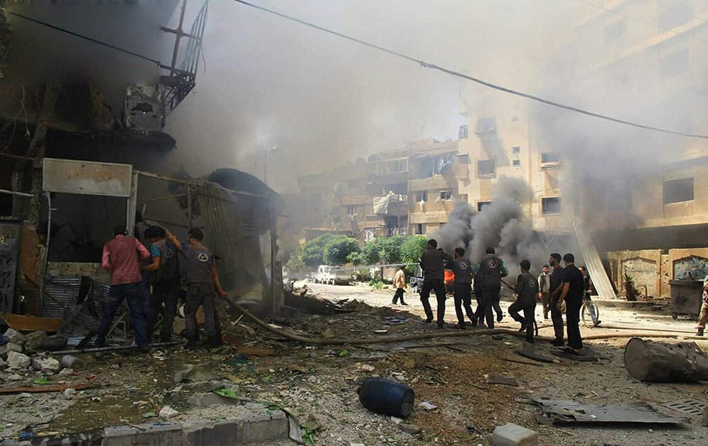 This photo provided by the Syrian anti-government activist group Douma Revolution, which has been authenticated based on its contents and other AP reporting, shows Syrian firefighters extinguishing a burning shop after a Syrian government airstrike, in Douma, a suburb of Damascus, Syria.