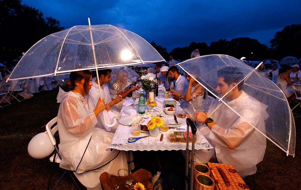 Eleanore Ryan, left, visiting from Los Angeles, and Joe Sobanko use their umbrella's during the Diner en Blanc event at the Navy Yard in Philadelphia.