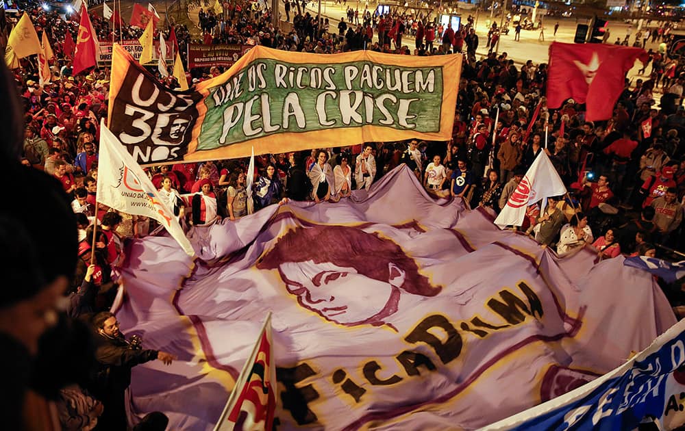 Demonstrators holding banners that read in Portuguese 'Let the rich pay for the crisis' and 'Stay Dilma,' gather in support of Brazil's President Dilma Rousseff in Sao Paulo, Brazil.