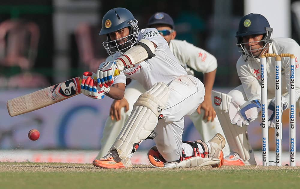 Sri Lanka's Kaushal Silva plays a shot as India's wicketkeeper Wriddhiman Saha watches during the second day's play of the second test cricket match between them in Colombo, Sri Lanka.