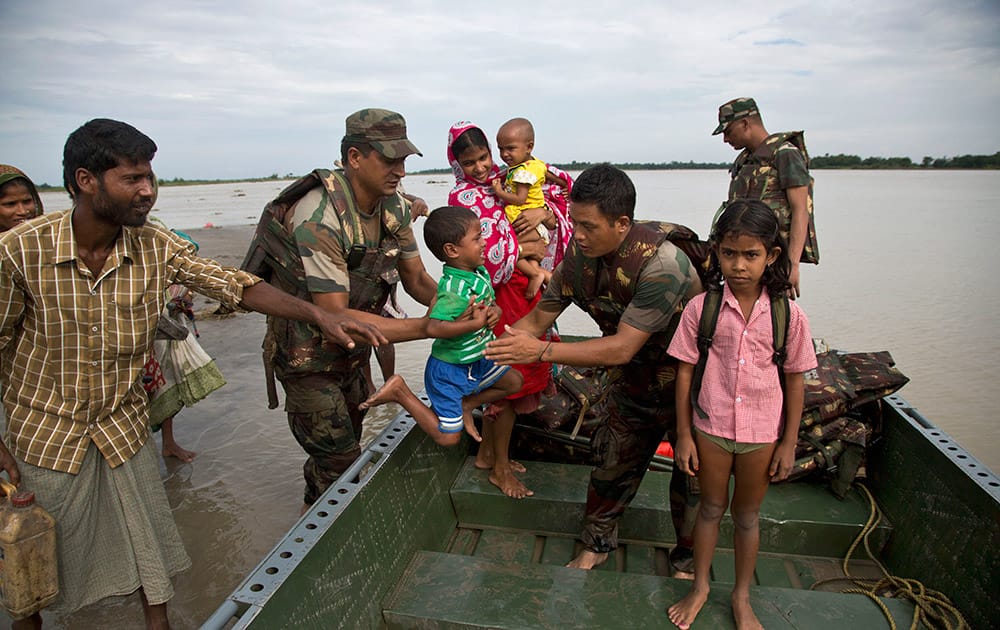 Indian army personnel transport flood-affected villagers to safer areas in a boat in Jaraguri village, about 160 kilometres (99 miles) west of Guwahati.