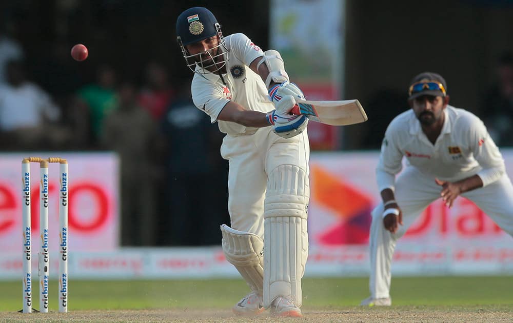 Ajinkya Rahane plays a shot as Lahiru Thirimanne watches during the third day's play of the second test cricket match between them in Colombo, Sri Lanka.