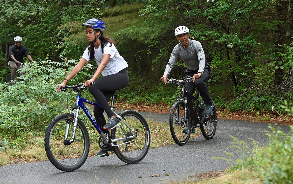 President Barack Obama follows his daughter Malia as they rides their bikes in West Tisbury, Mass., on Martha's Vineyard.