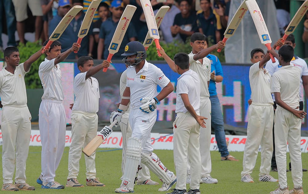 Sri Lanka national team player Kumar Sangakkara walks trough an arch of bats as he arrives in the field to bat in his final test innings during the fourth day's play of the second test cricket match between Sri Lanka and India in Colombo, Sri Lanka