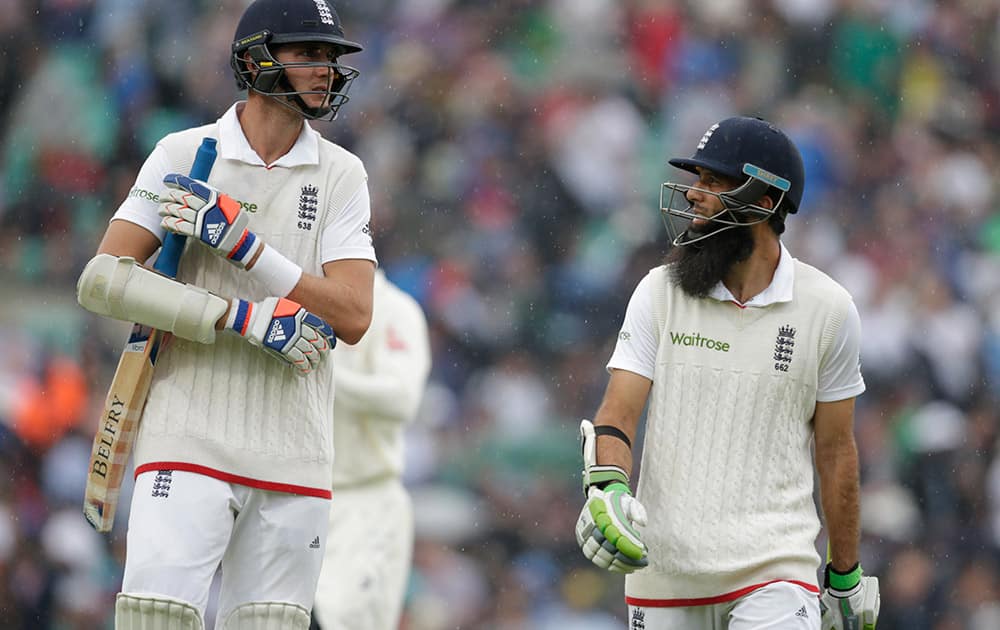 England’s Moeen Ali, right and England’s Stuart Broad walk off the pitch as rain falls to delay the match on the forth day of the fifth Ashes cricket test between England and Australia at the Oval cricket ground in London.