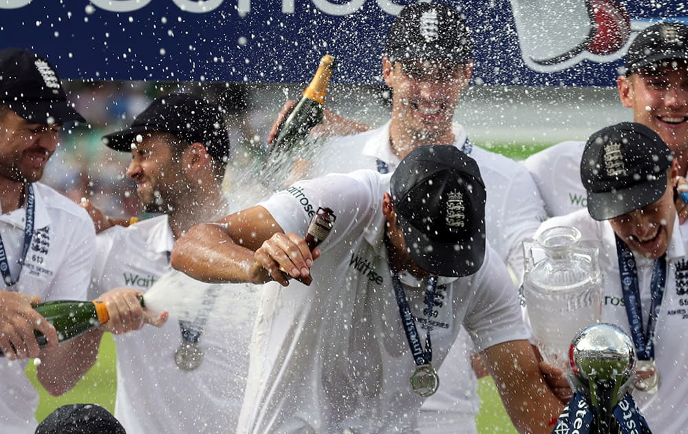 England’s captain Alastair Cook covers his face as he is sprayed with champagne during a presentation ceremony on the forth day of the fifth Ashes cricket test between England and Australia at the Oval cricket ground in London.