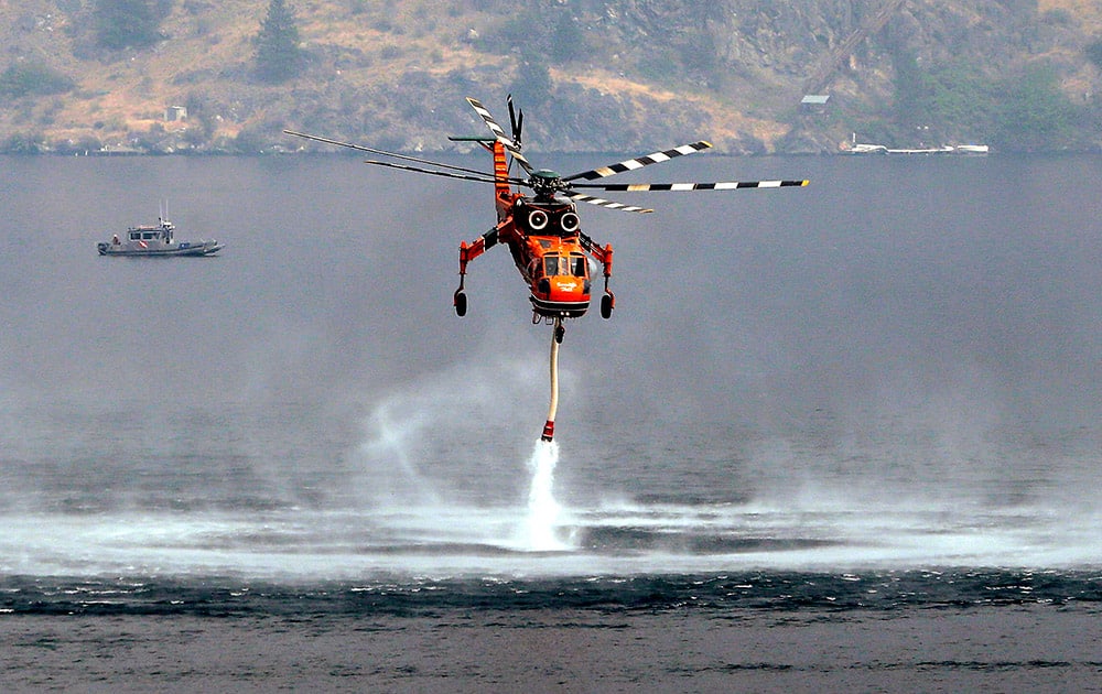 A firefighting helicopter begins to pull up after filling up with water from Lake Chelan in Chelan, Wash. 