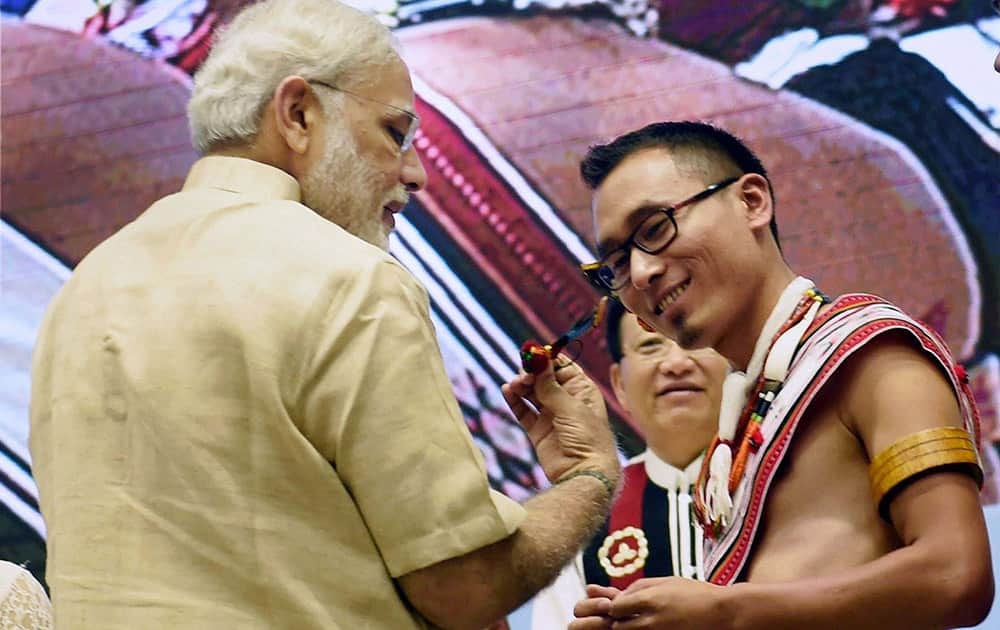 Prime Minister Narendra Modi having a look of the ear-rings of a Naga tribal artist at the inaugural function of the birth centenary of Rani Gaidinliu, in New Delhi.