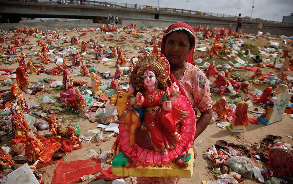 A  woman collects idols of Hindu goddess Dashama left by devotees on the banks of the River Sabarmati at the end of Dashama festival in Ahmadabad.