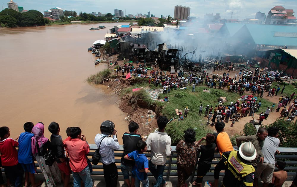 Local residents standing on Bassac river bridge watch a fire in a squatter community, at Tonle Bassac river bank, in Phnom Penh, Cambodia. A district official said about 36 families lost their homes at the river bank in Phnom Penh's Chbar Ampov district. 